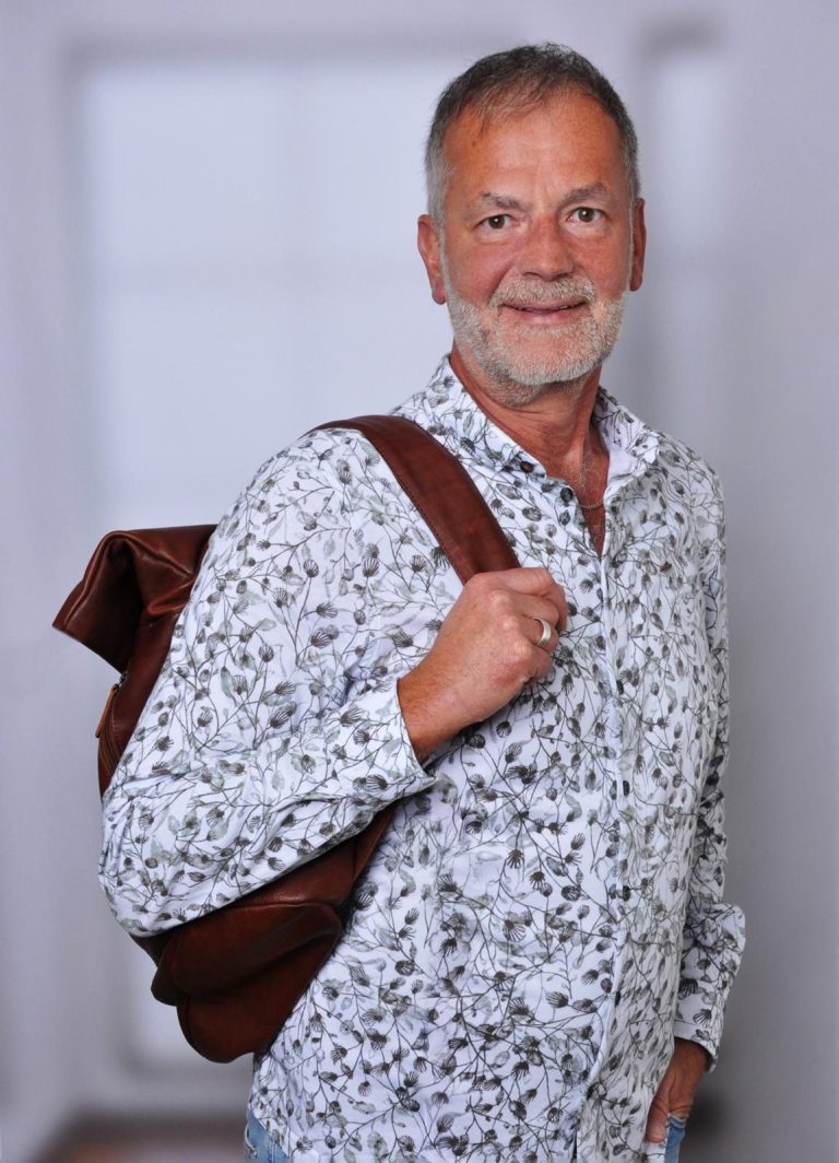Ralf Nothdurft Ralf Nothdurft mit brauner Tasche, lächelnd, trägt ein gemustertes Hemd.